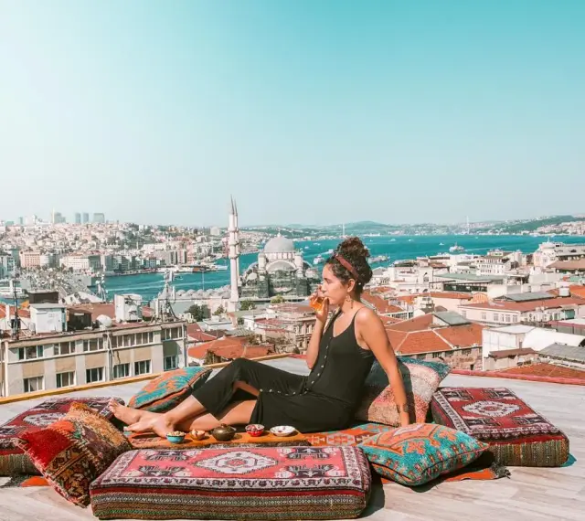 A woman enjoys a drink on a rooftop overlooking Istanbul, a scene straight out of a Rick Steves Turkey adventure.